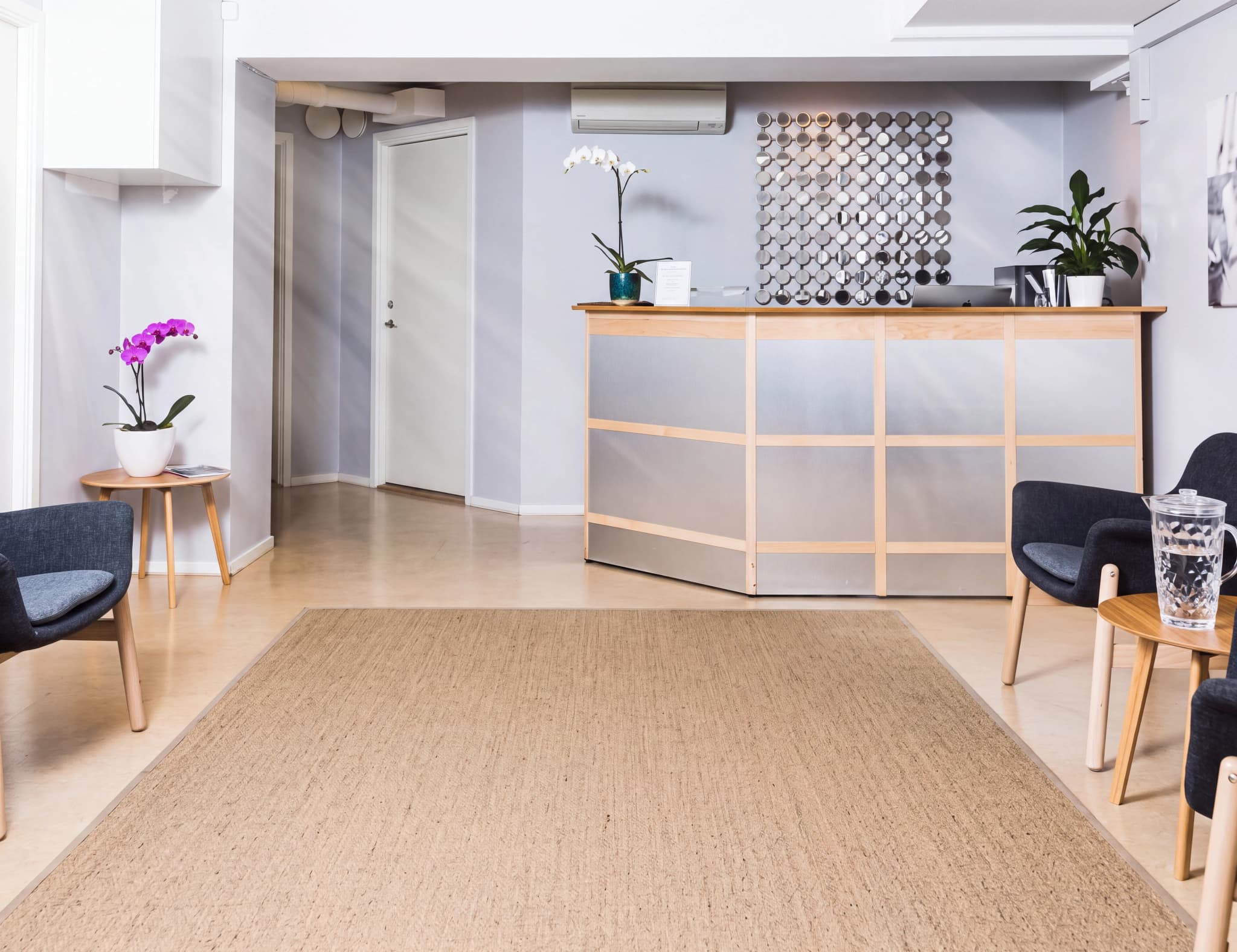 Reception och väntrum på en klinik med en disk, stolar och en matta