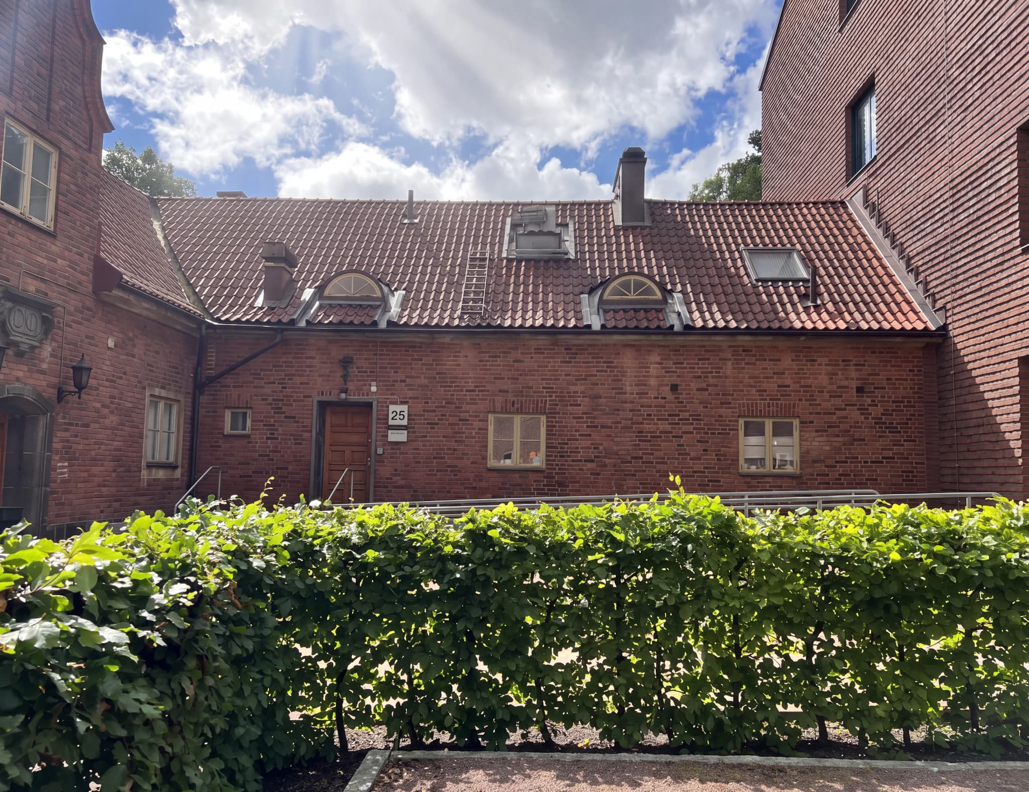 Exteriör av en tegelbyggnad med ett tak av tegelpannor en solig dag.