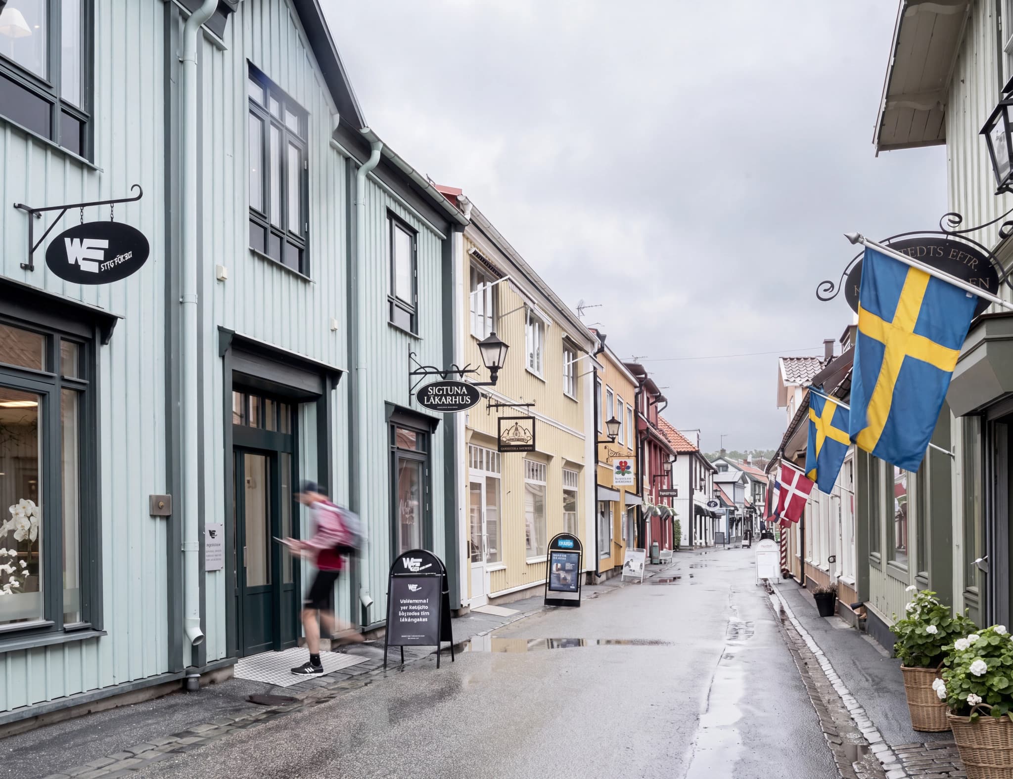 En svensk stadsgata med flaggor och butiker.