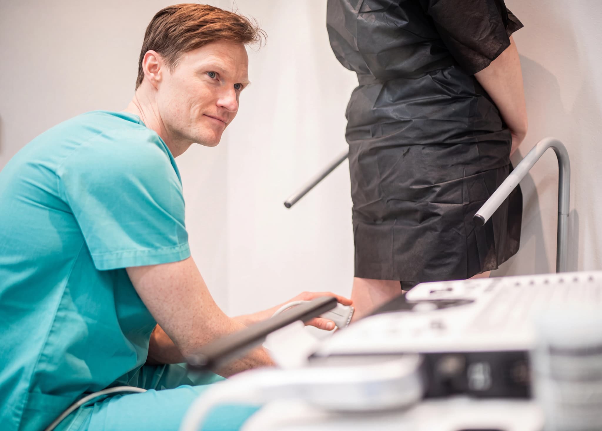 Läkare utför ultraljudsundersökning på en patients ben i ett undersökningsrum