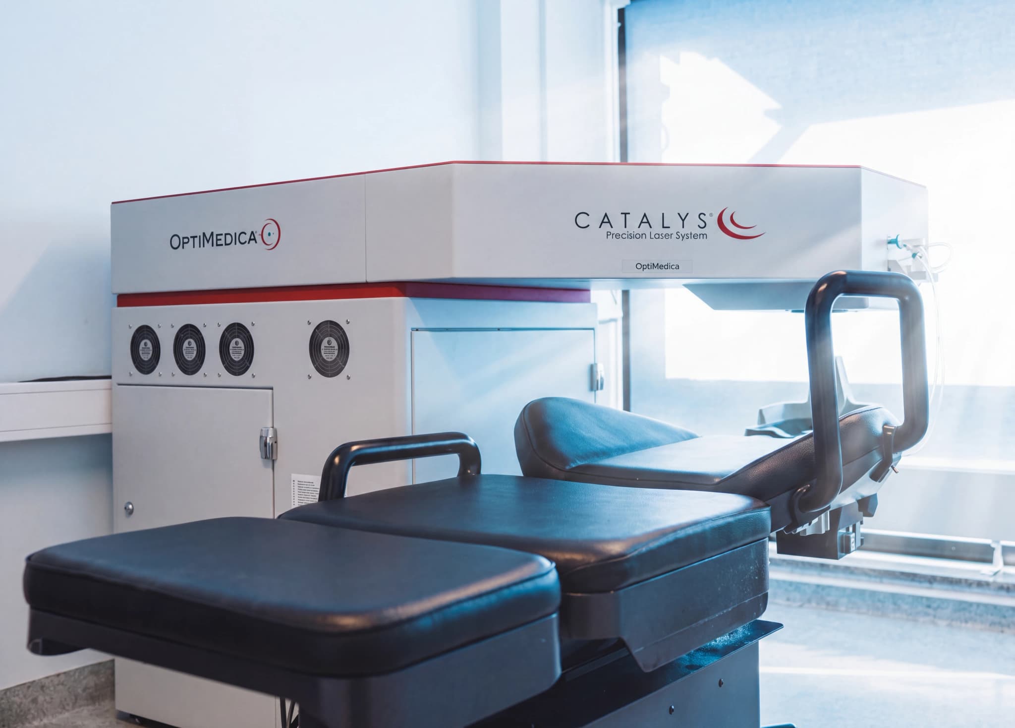 OptiMedica Catalys precisionslasersystem med en behandlingsstol framför.