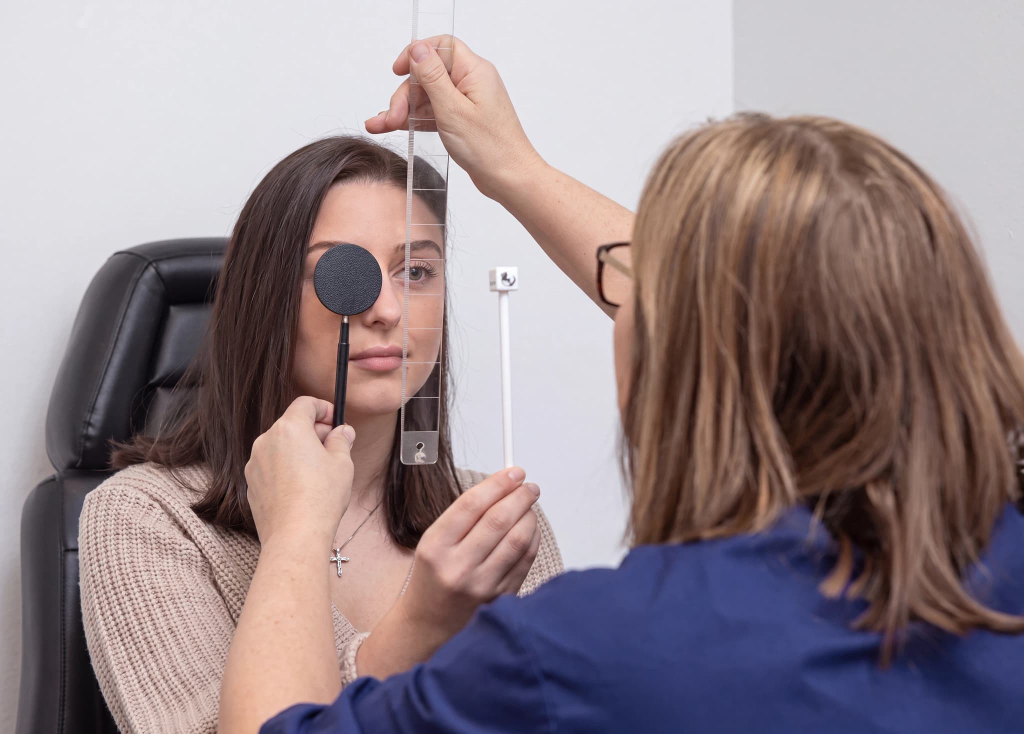 Optiker undersöker patientens öga med en ockluder under ett synprov.
