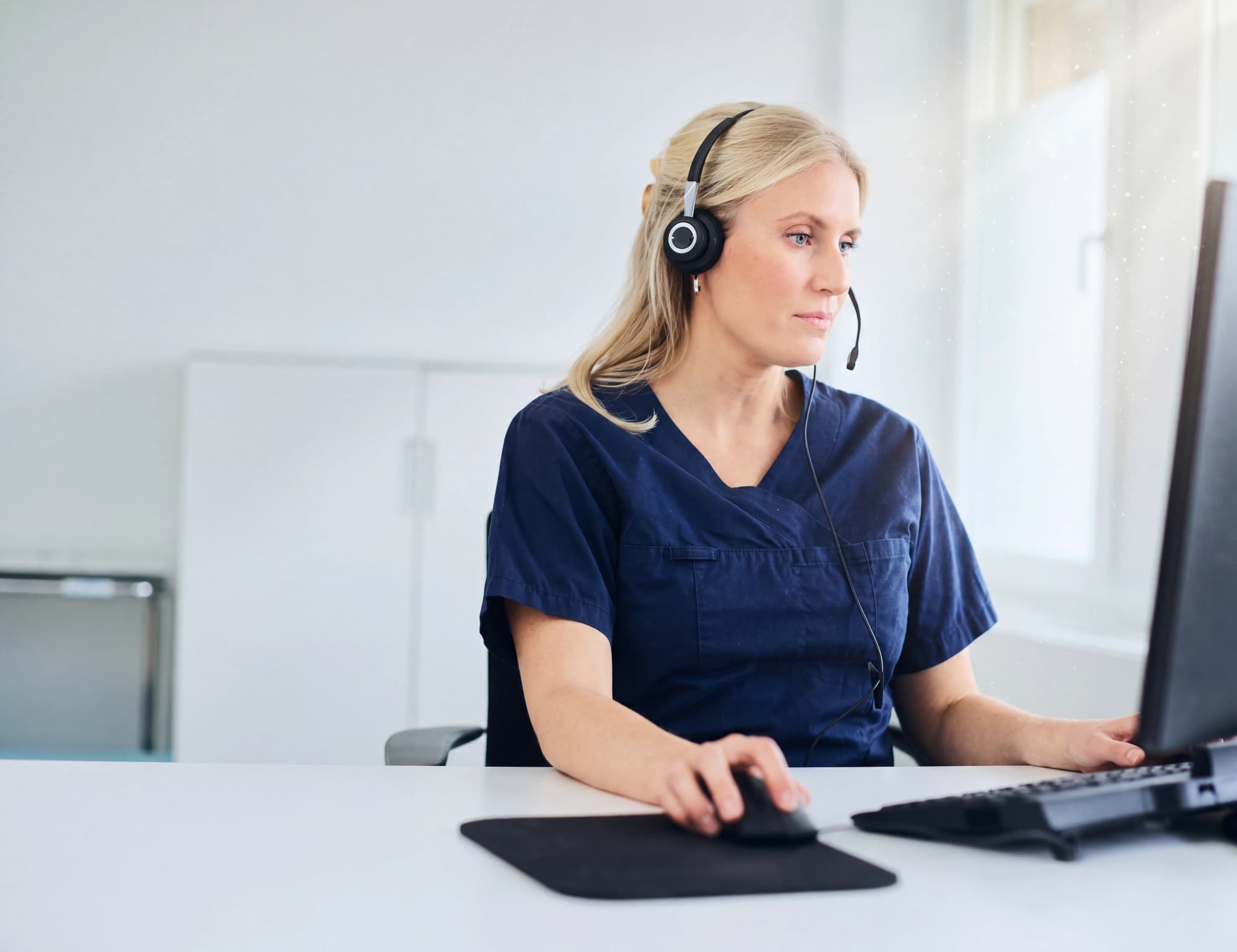 Sjuksköterska med headset som arbetar vid en dator