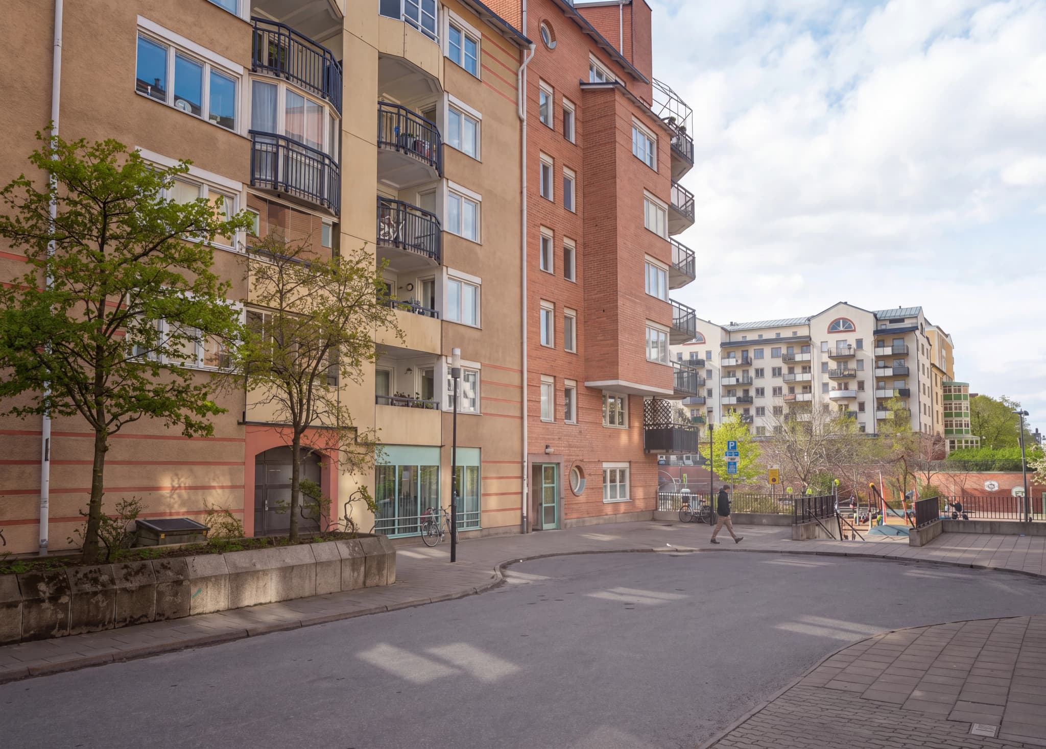 Exteriör av ett flerfamiljshus med träd och en trottoar framför.