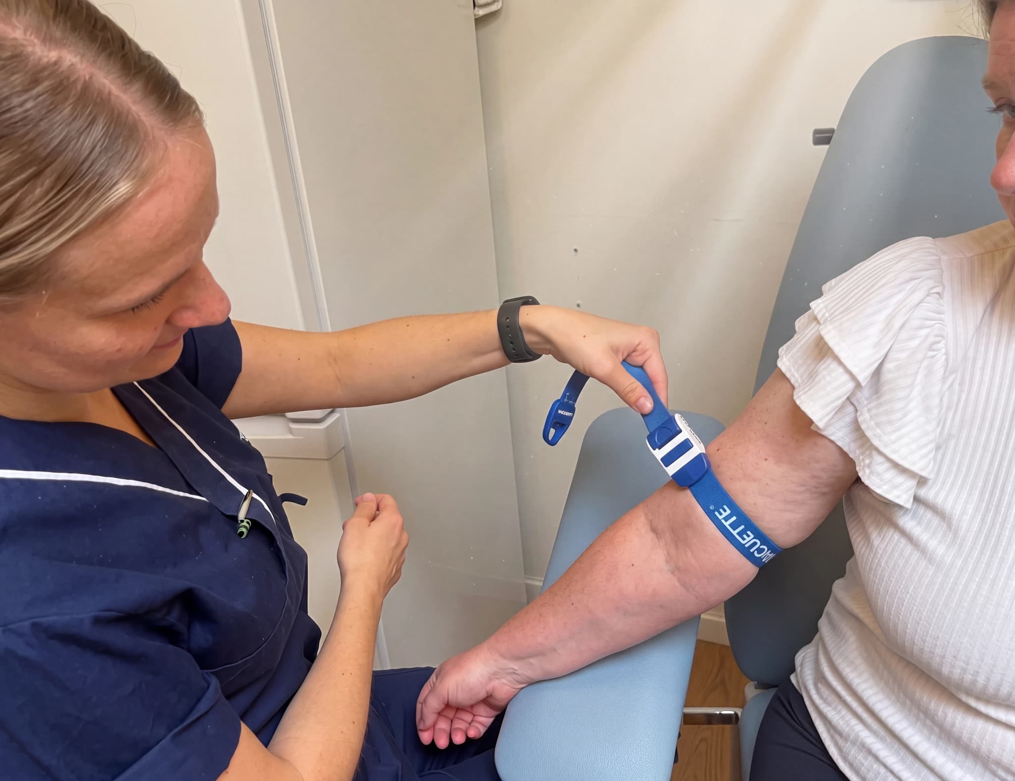 Sjuksköterska sätter på en venös tryckmanschett på patientens arm innan blodprovstagning.