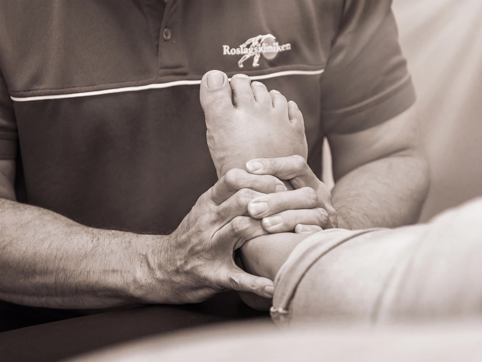 En terapeut masserar en patients fot och fotled i en klinik.