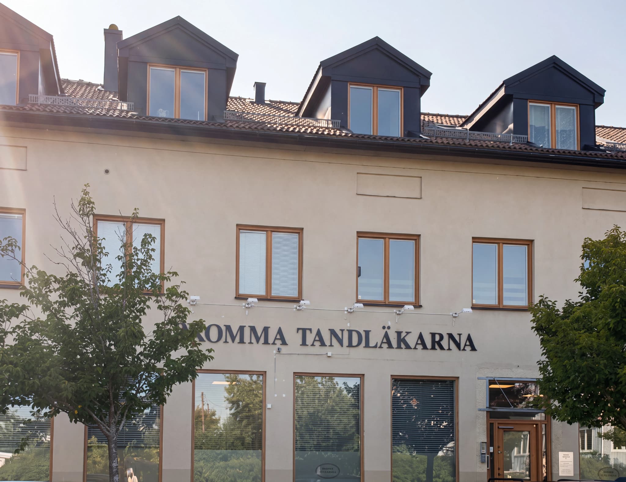 Fasad av en byggnad med texten "KOMMA TANDLÄKARNA" ovanför fönstren.