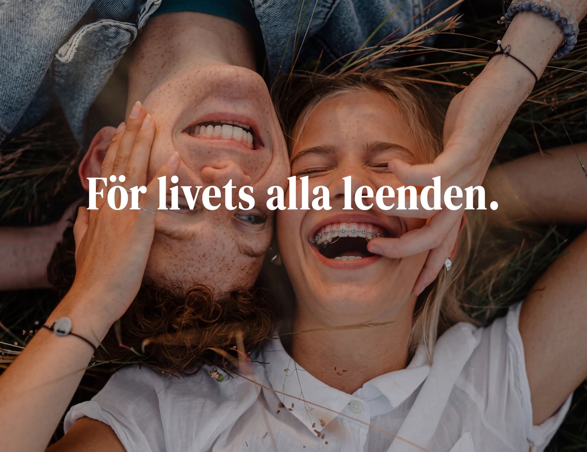 Ett par ligger på rygg och ler glatt. Den ena personen har tandställning.