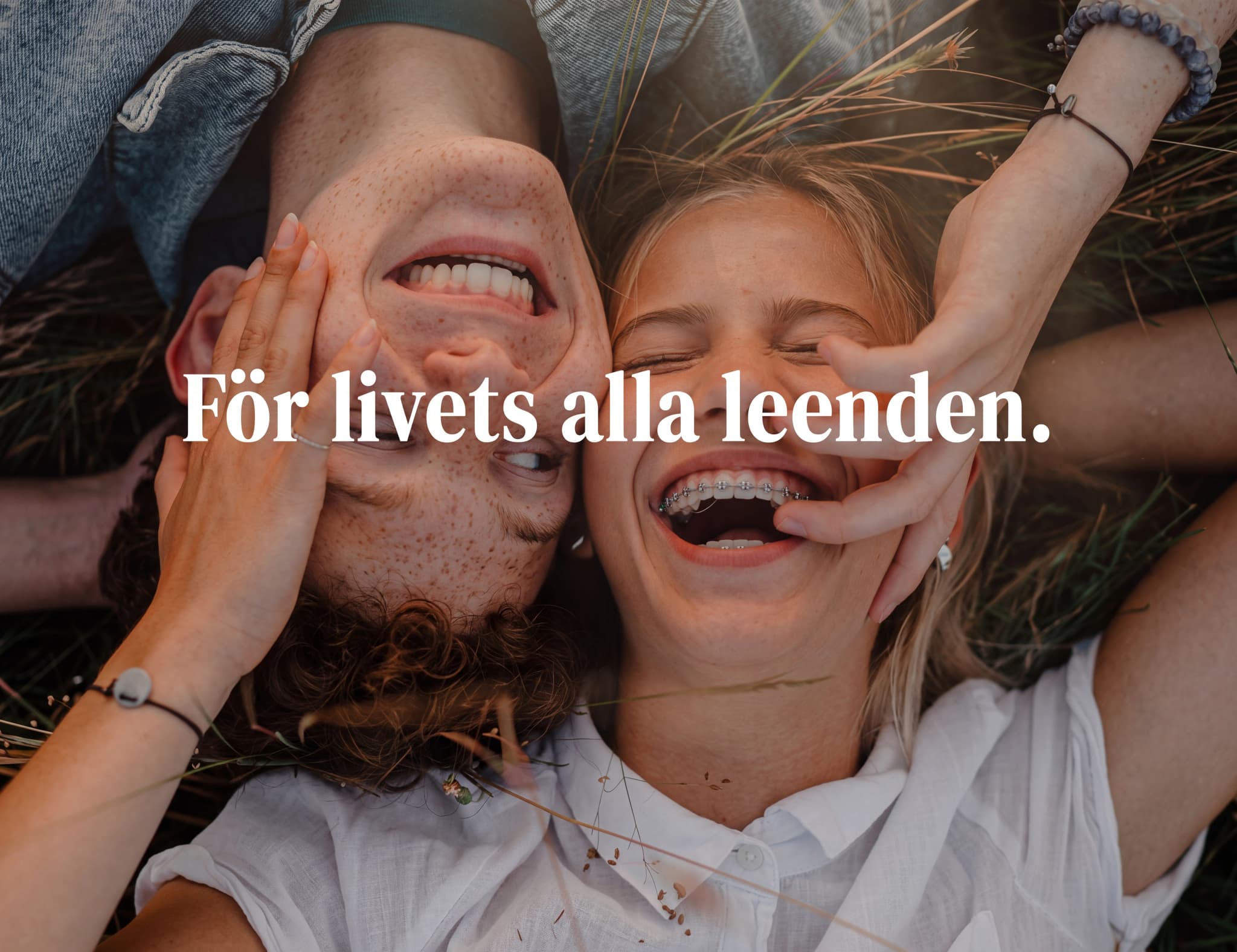 Ett skrattande ungt par som ligger på en gräsmatta med gräs runt omkring dem. Texten 'För livets alla leenden.' är överlagd.