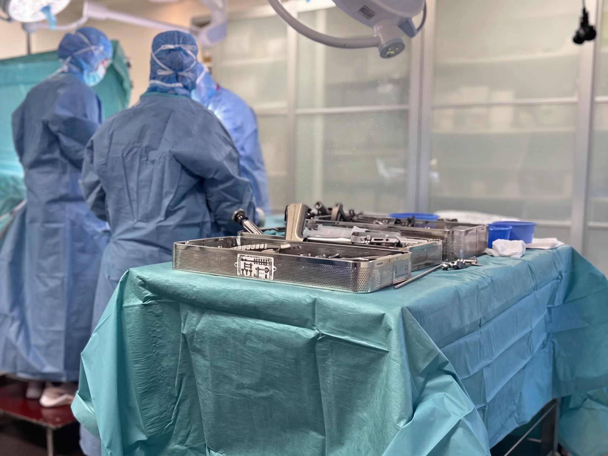 Kirurger i operationskläder förbereder medicinska instrument på ett bord i ett operationsrum.