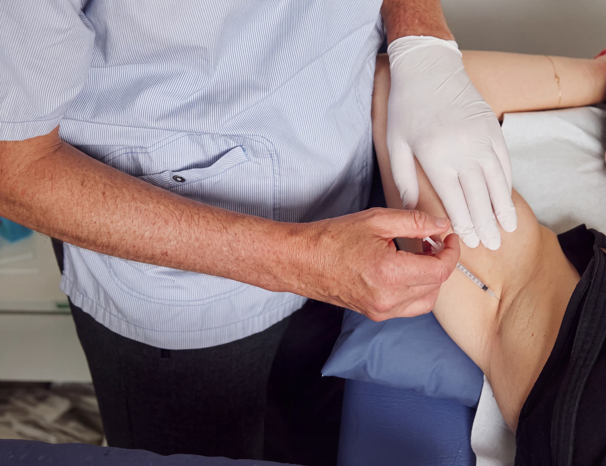 En vårdgivare i handskar ger en injektion i armen på en patient.