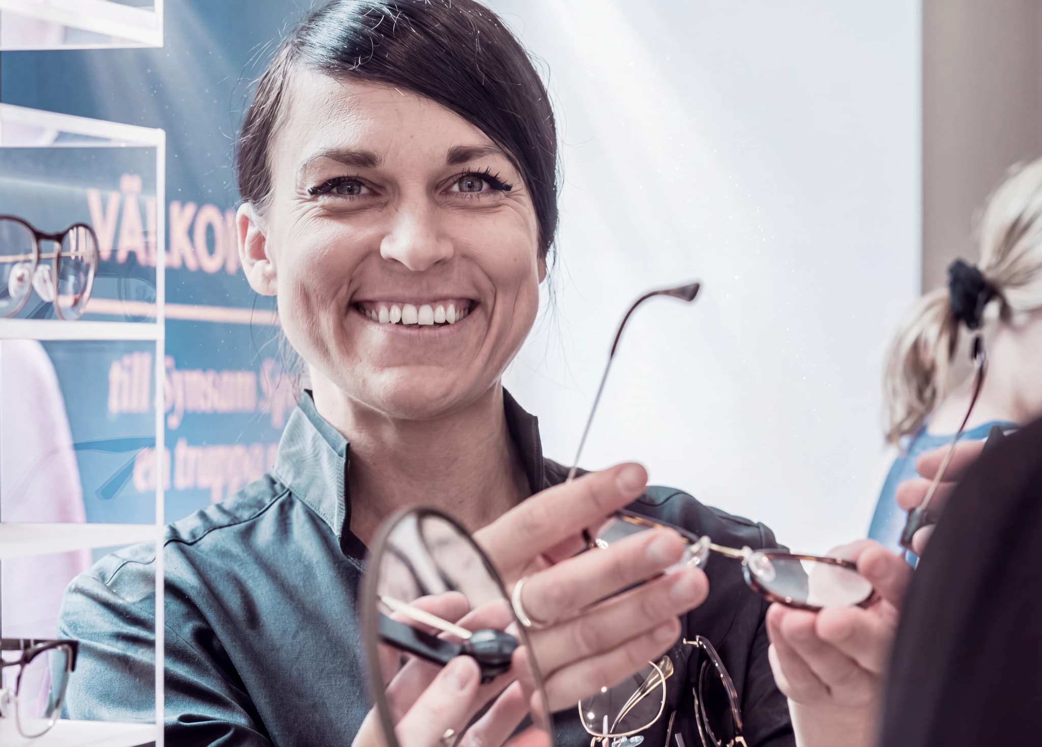 Optiker visar ett par glasögon för en kund i en butik.