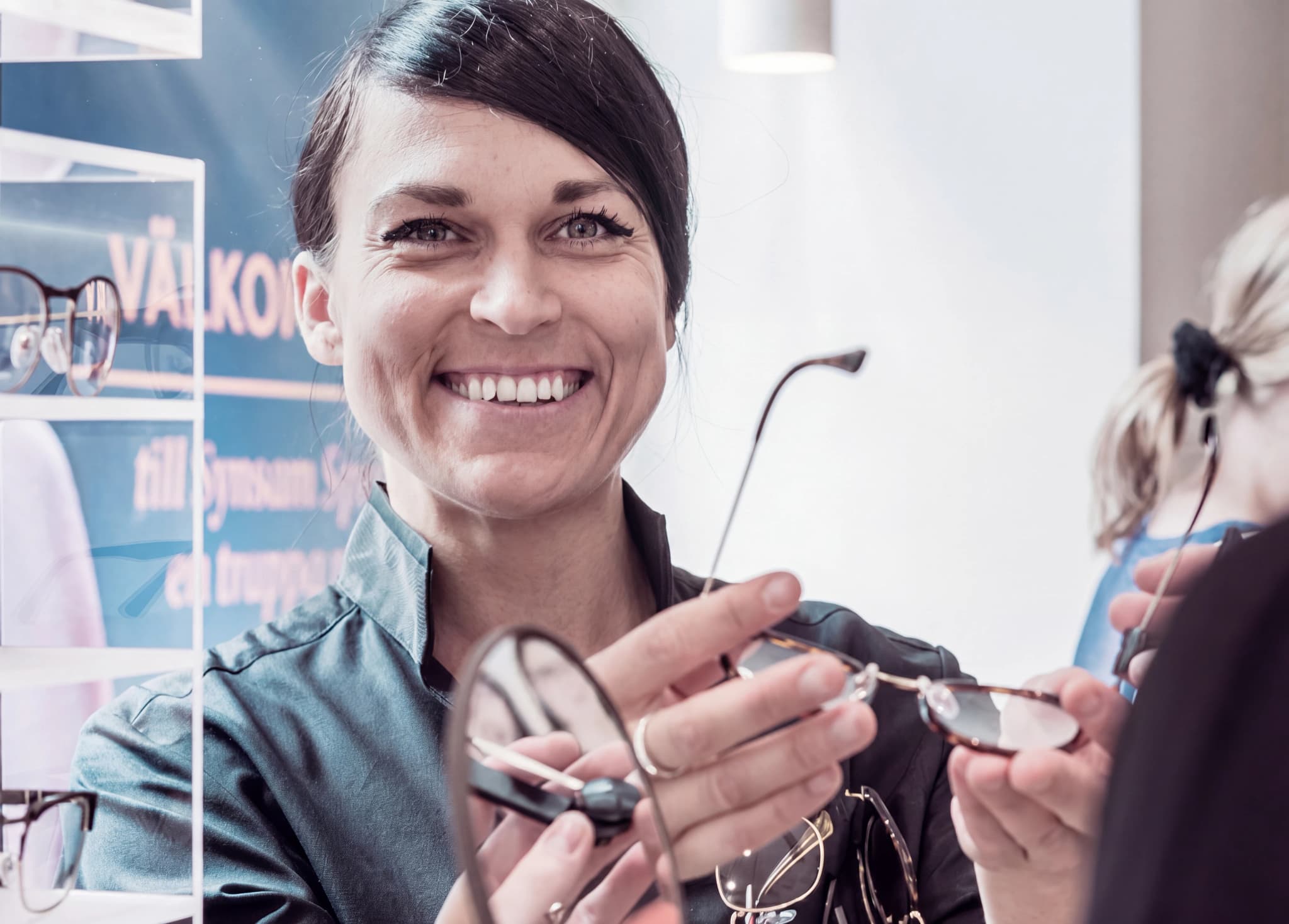 Optiker visar ett par glasögon för en kund i en butik.