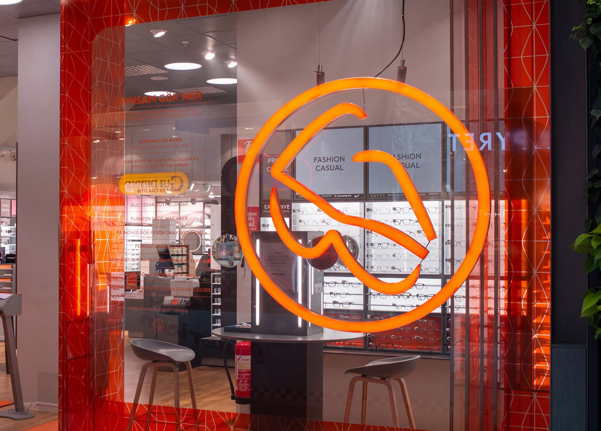 Fönsterdisplay i en optikerbutik med neonlogga och glasögonexempel.