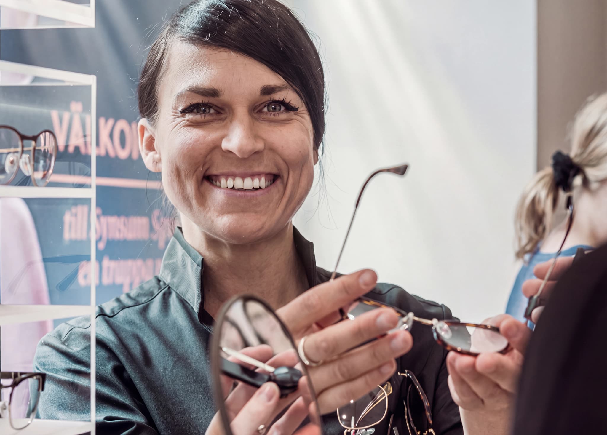 Optiker hjälper en kund att prova glasögon i en butik.
