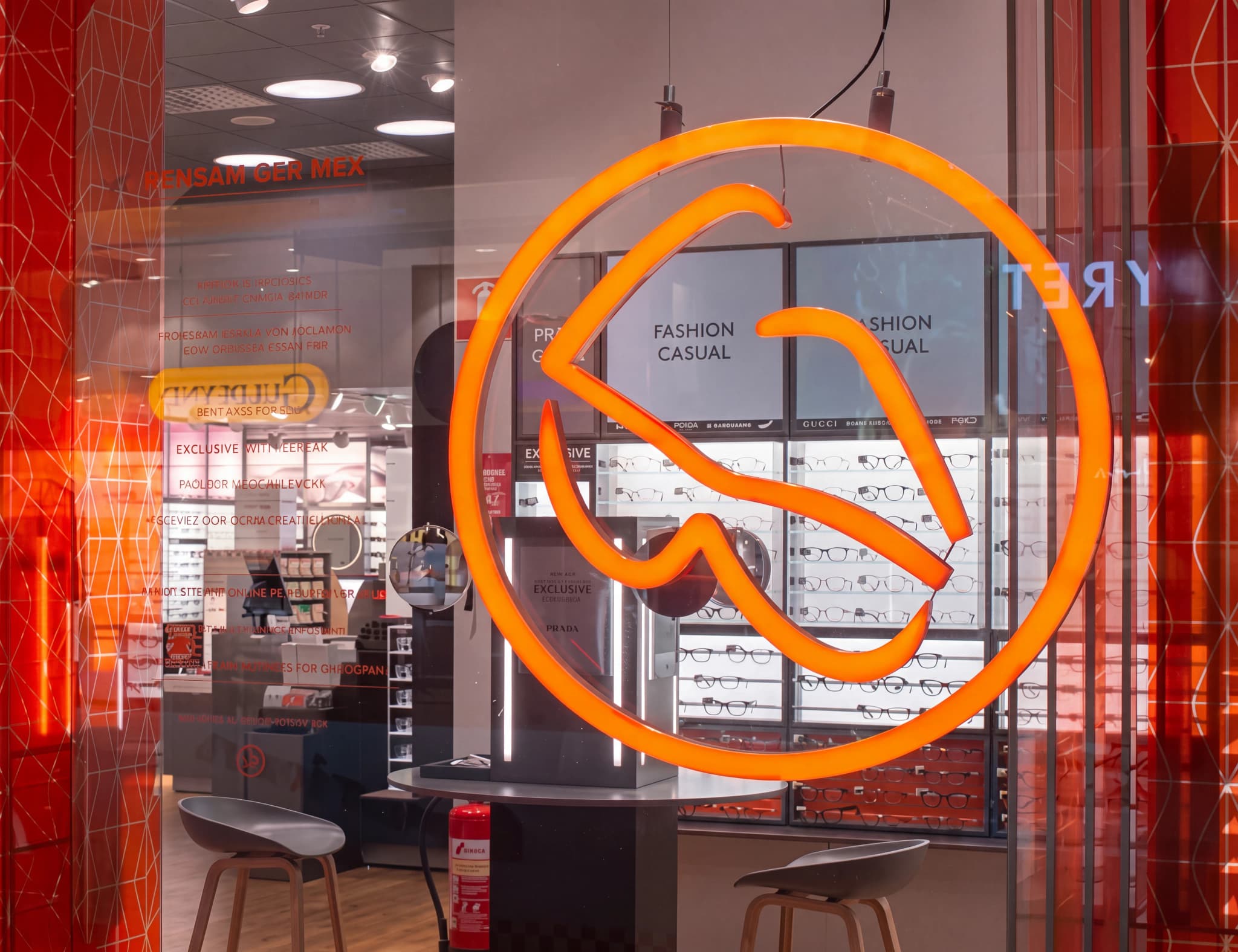Fönsterdisplay i en optikbutik med orange logotyp och glasögon i bakgrunden.