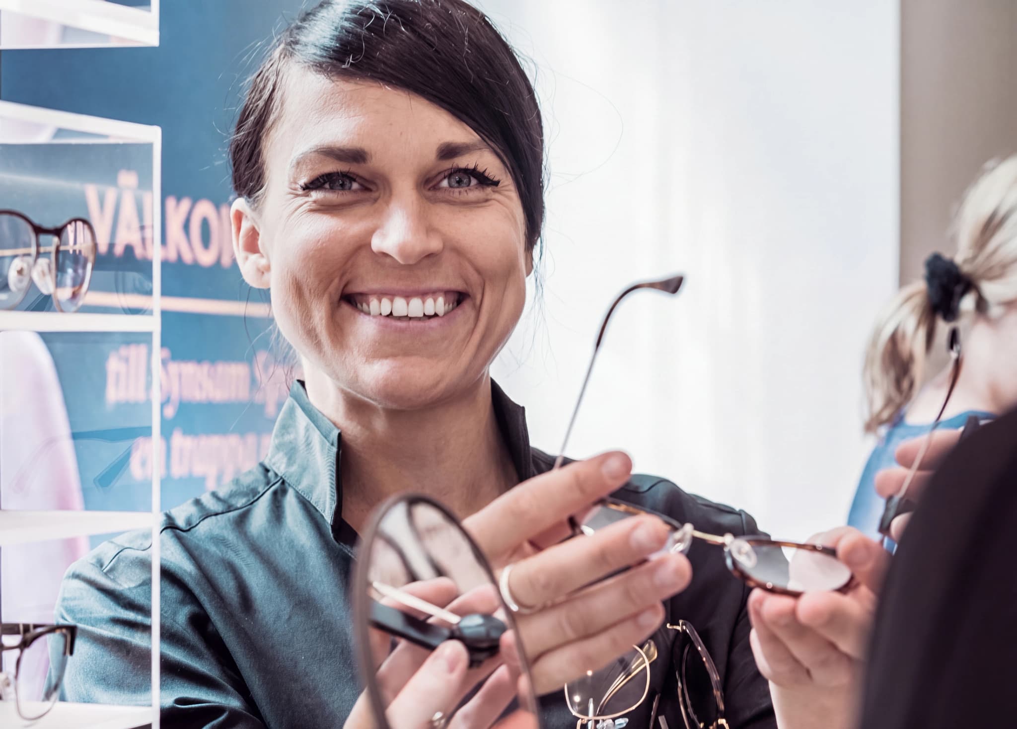 Optiker visar glasögon för en kund i en butik.