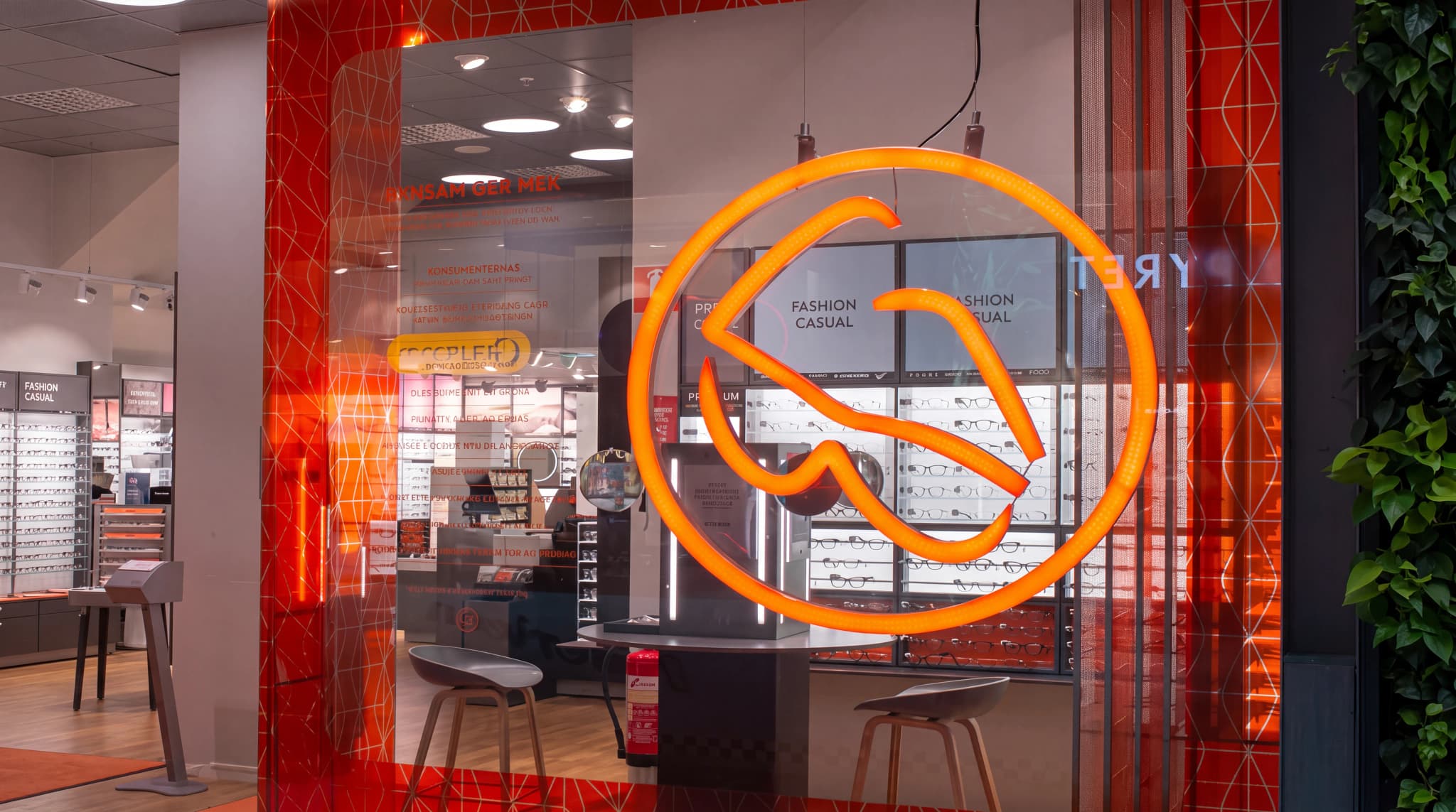 Fönsterdisplay i en optikerbutik som visar glasögon och en neonlogotyp.