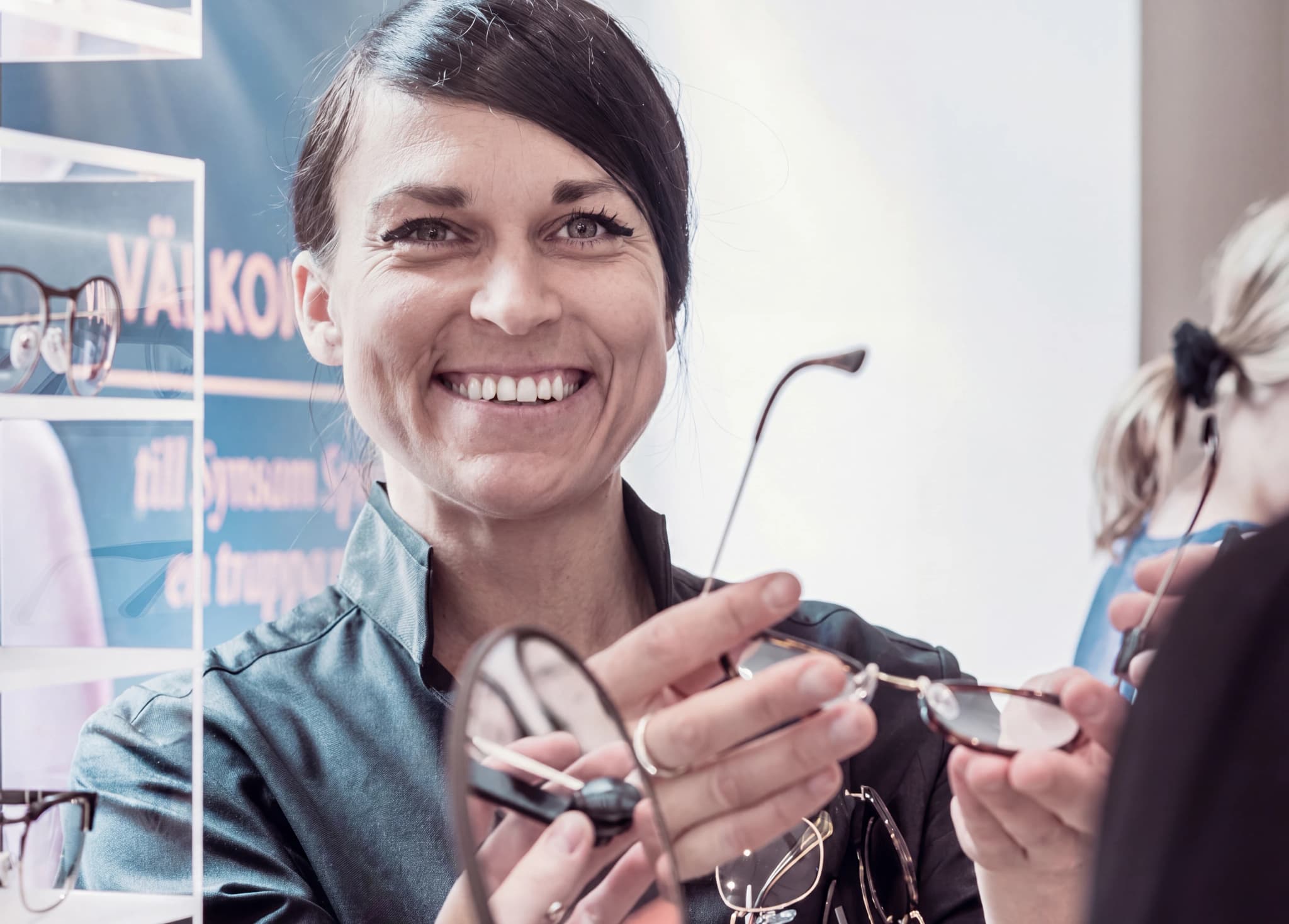 Optiker visar upp glasögon för kund i en butik eller mottagning.