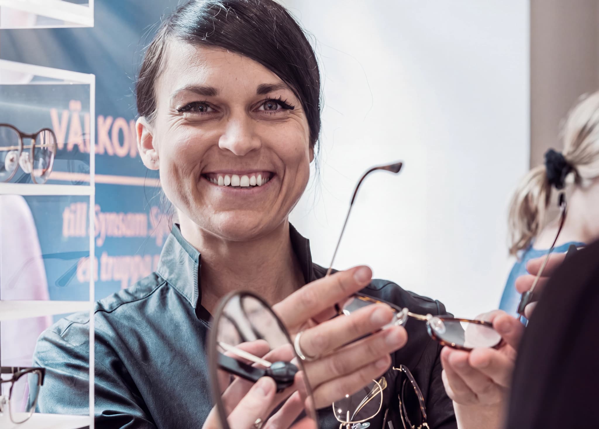 Optiker visar glasögon för en kund i en butik.