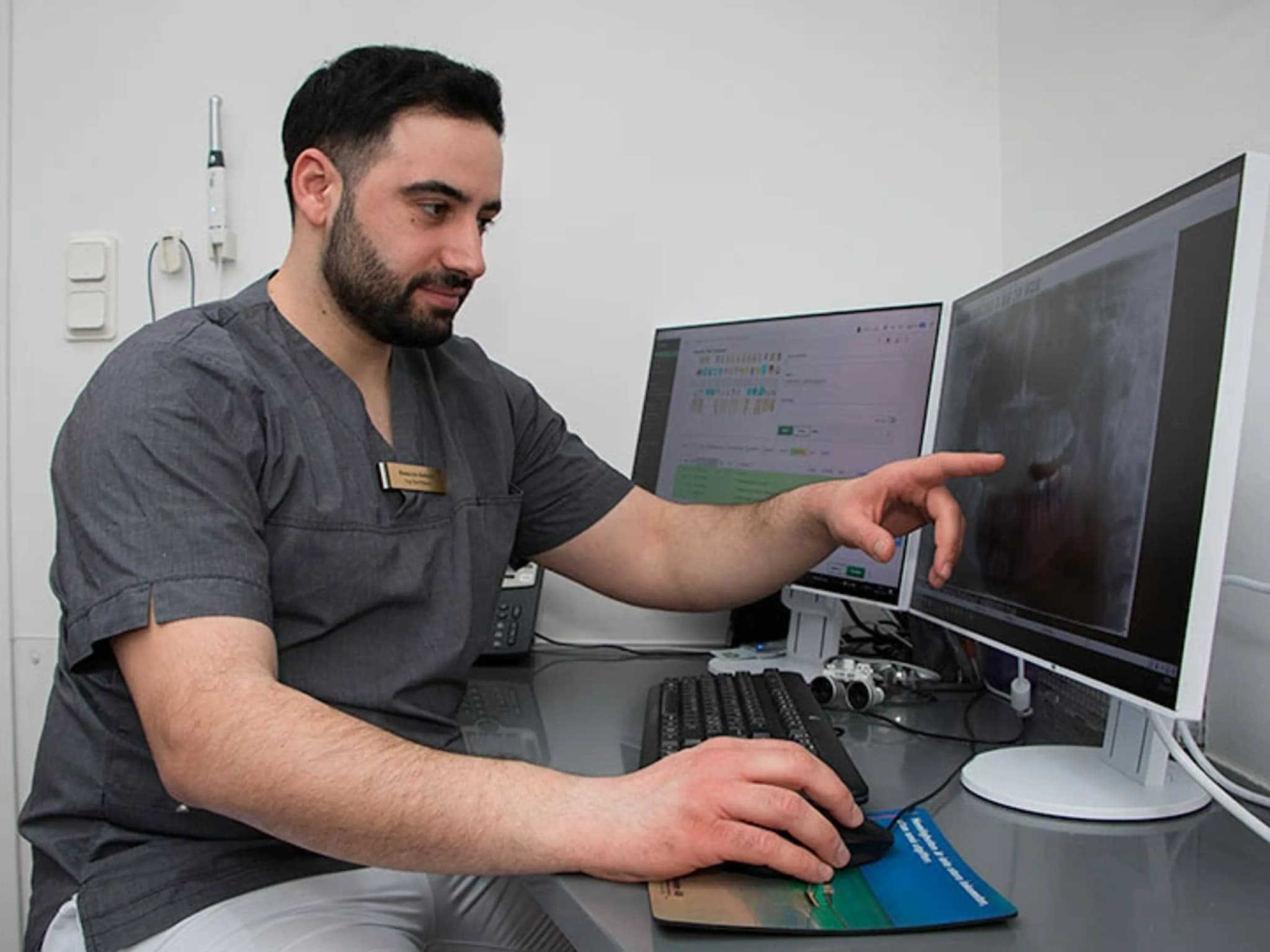 Tandläkare som granskar ett dentalröntgenfoto på en datorskärm.