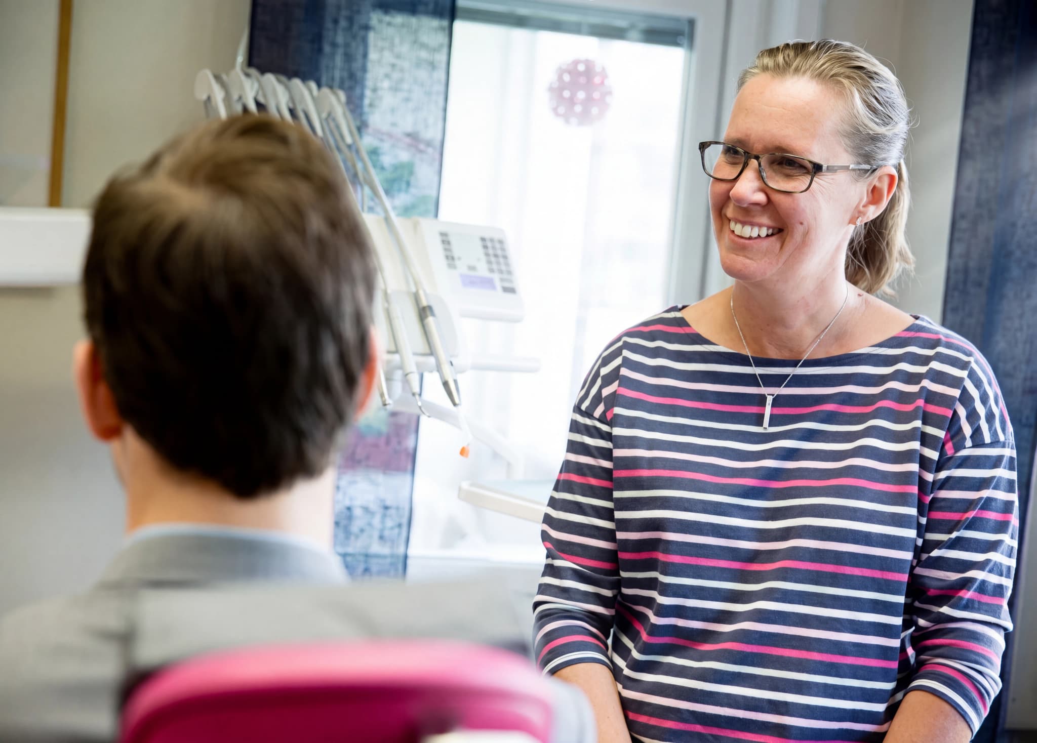 Tandläkare ler mot en patient i ett undersökningsrum.