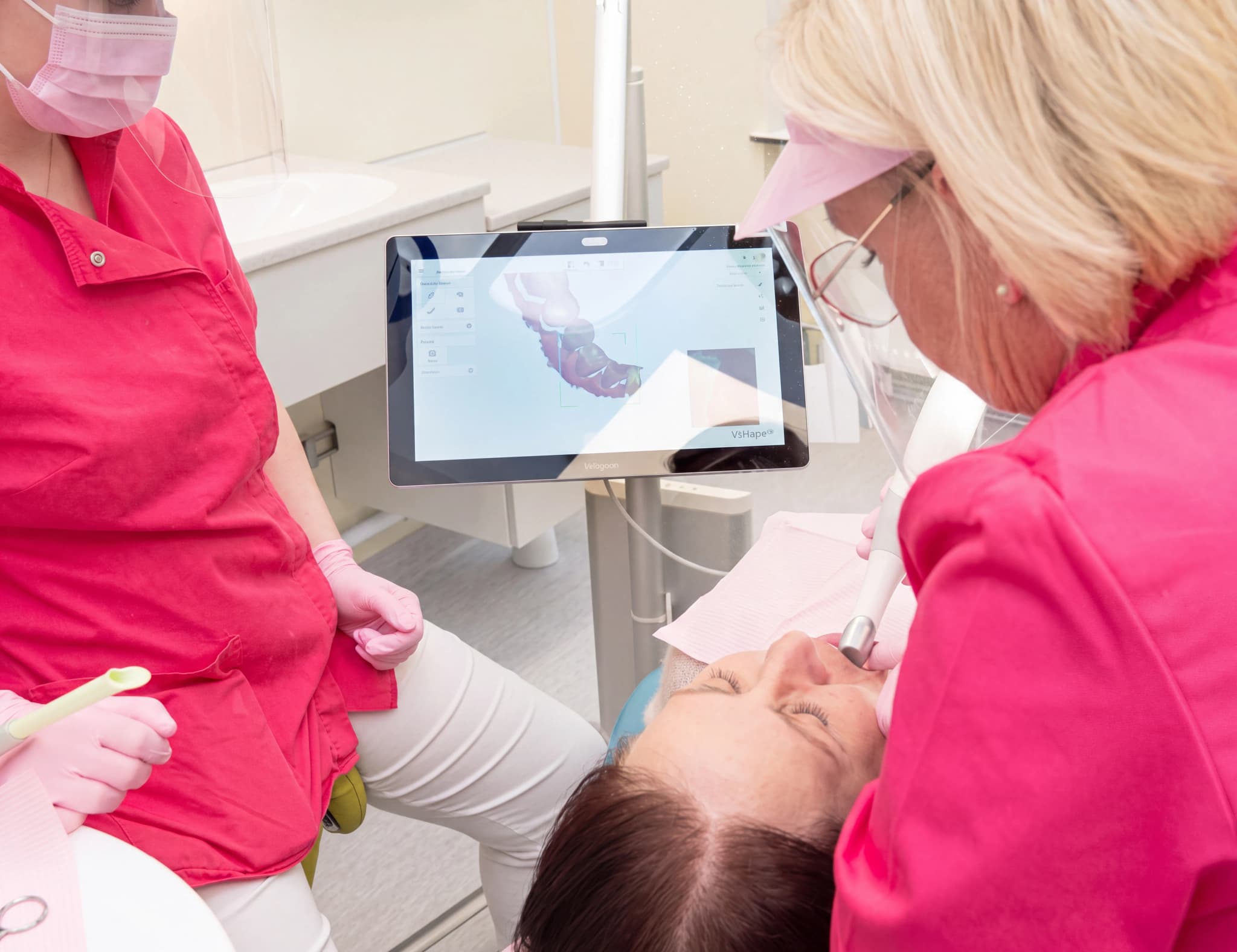 Tandläkare använder en intraoral skanner för att skanna en patients tänder i en behandlingsrum.