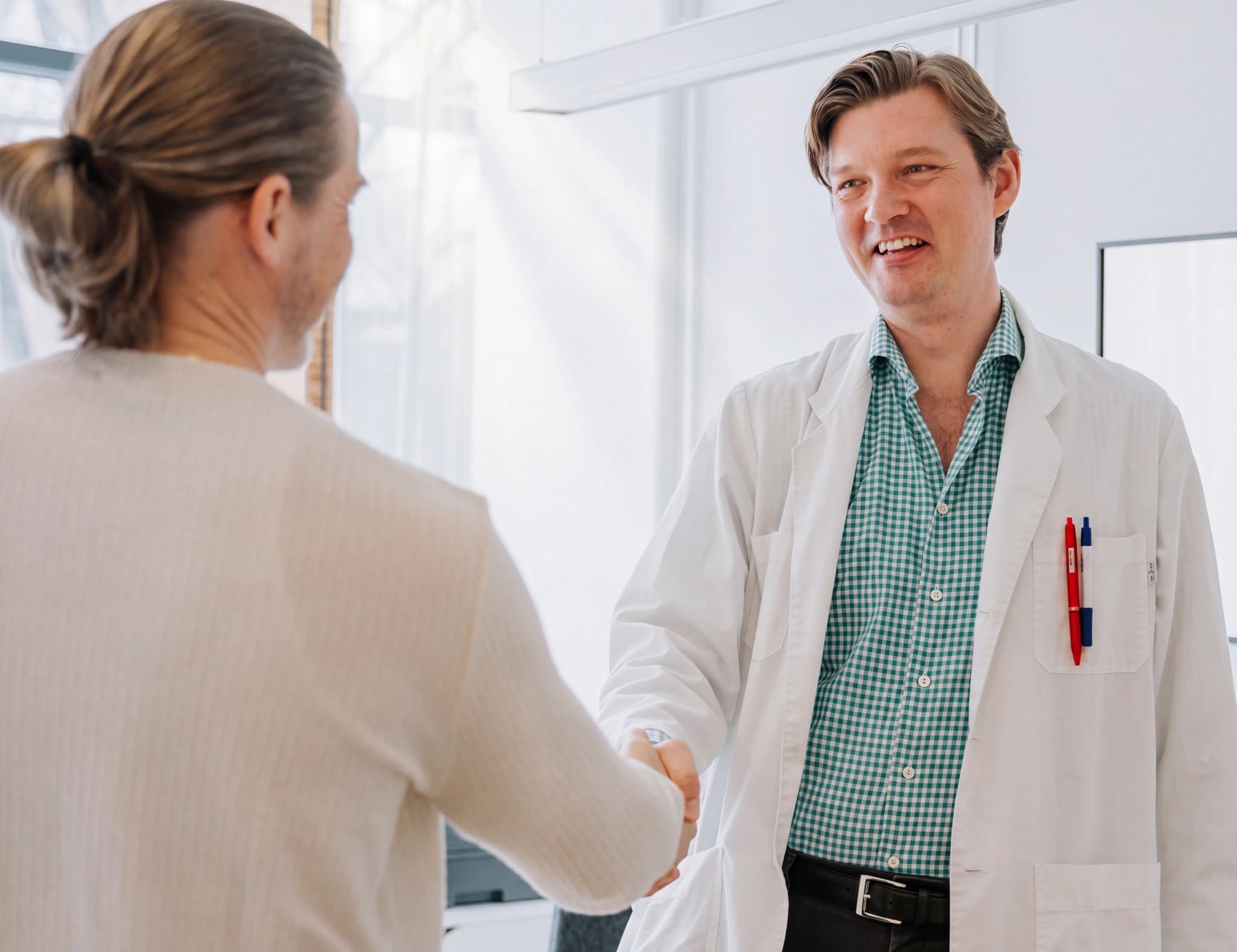 Läkare i vit rock skakar hand med en patient