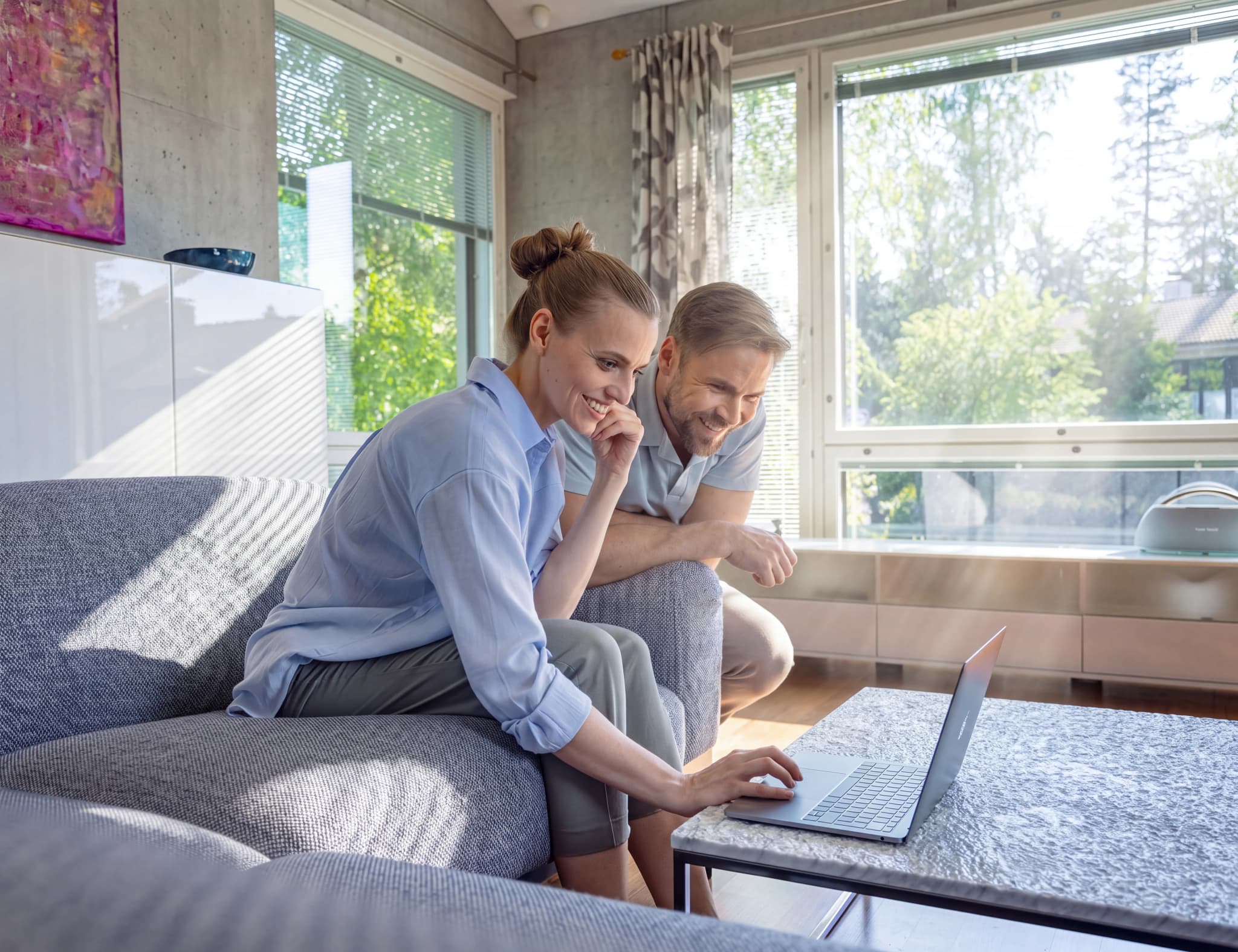 En man och en kvinna sitter i en soffa och tittar på en laptop