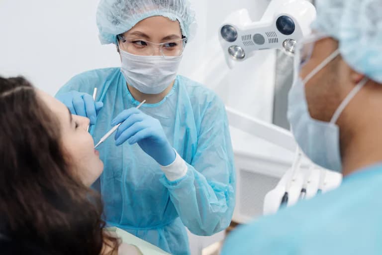 Tandläkare undersöker en patient i munnen med instrument på en tandläkarmottagning.