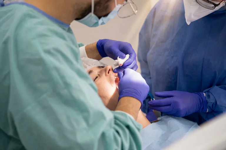 Tandläkare undersöker en patients mun med verktyg och bomull.