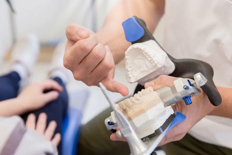 Tandläkare som förklarar en tandmodell för patienten på en tandklinik.