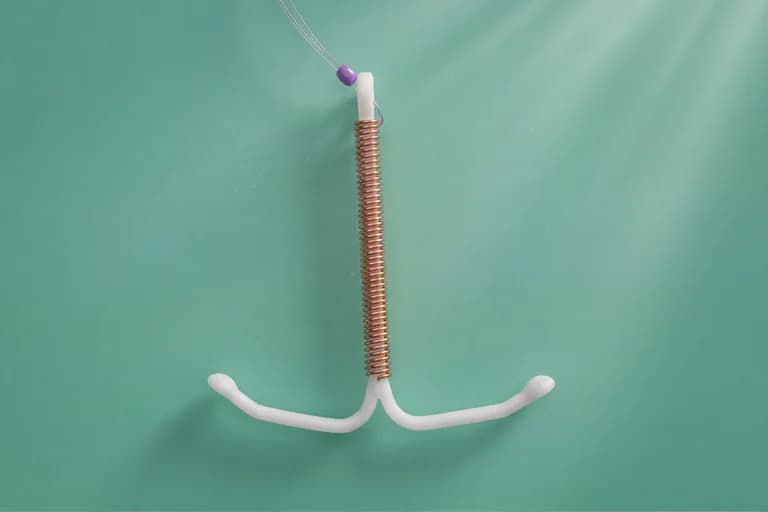 Ett intrauterint preventivmedel (IUD) i form av ett T-format plastinstrument med en spiral av koppartråd lindad runt en stomme, med tunna trådar hängande ner från toppen, på en turkos bakgrund.