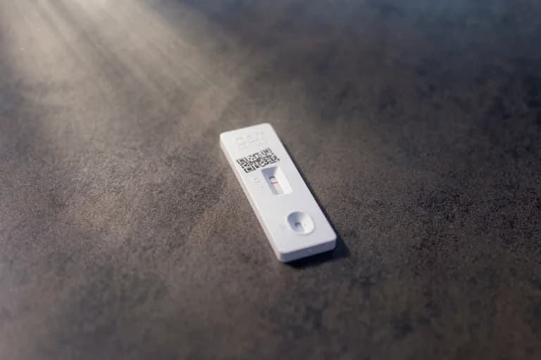 Ett covid-19-snabbtester visar ett negativt resultat med ett kontrollstreck och ett svagt teststreck på ett mörkt bord.