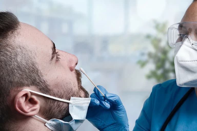 Sjukvårdspersonal tar ett nasalt pinprov på en patient.