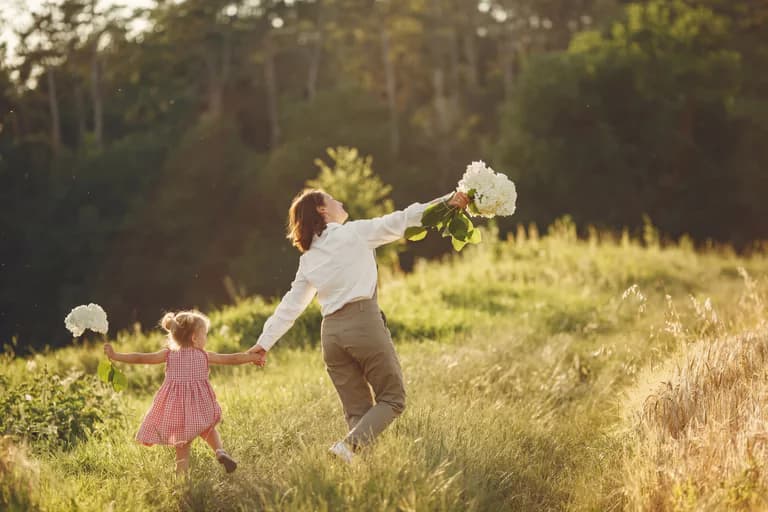 En mamma och hennes dotter dansar lyckligt i ett soligt fält med blommor.